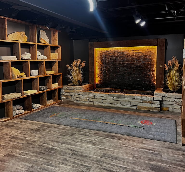 Modern interior space with wooden shelving unit, stone fireplace with warm lighting, decorative dried grass, and wooden flooring
